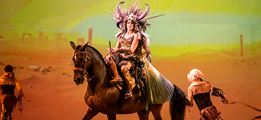 Rooliasuun pukeutunut nainen hevosen selässä naisten satulassa