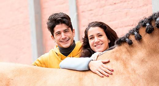 Siblings leaning over the back of a horse 