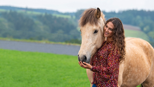 Kenzie Dysli avec un cheval islandais dans la verdure 