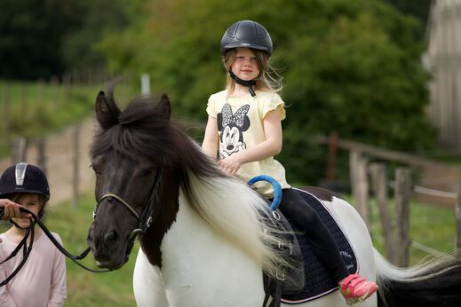 Mädchen reitet auf geschecktem Pony